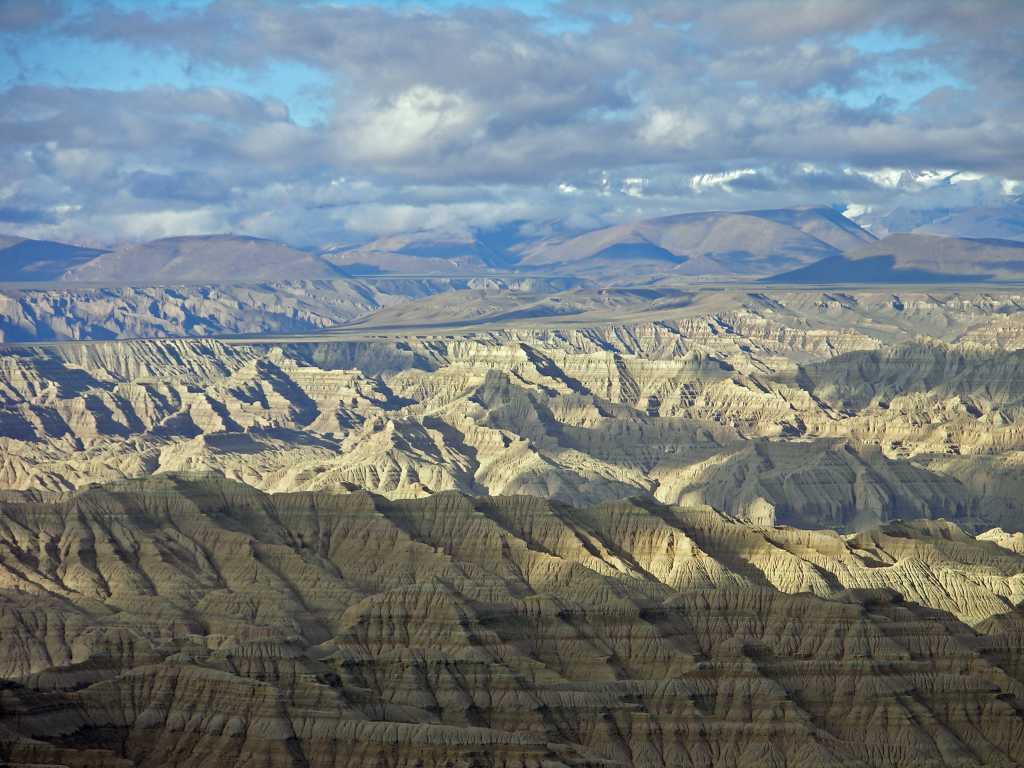 Tibet Guge 01 To 16 Sutlej Canyon As we got closer to Tholing, a broad view opened across the Sutlej canyon, a wild jumble of eroded sandstone hills, with the mountains of India in the distance. Kamet (7756m) is the tallest mountain, with its snowy rounded dome. This mountain has often been mistaken for Nanda Devi.